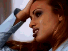 a close up of a woman 's face with her hand on her forehead .