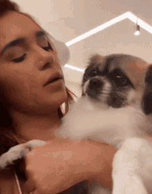 a woman holding a small brown and white dog in her arms
