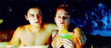 a man and a woman are sitting in a hot tub drinking a drink .