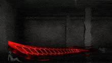 a woman sits in a dark room with a red light coming out of a wall