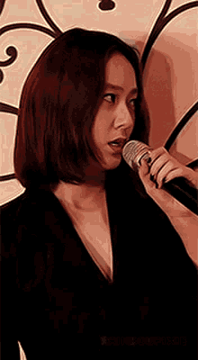 a woman with red hair is singing into a microphone in front of a wall