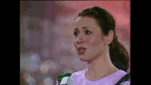 a woman in a purple shirt is talking into a microphone