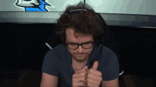 a man wearing glasses and headphones giving a thumbs up sign