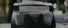 a stack of 100 dollar bills being counted by a machine