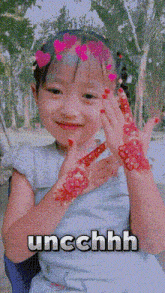 a little girl with henna on her hands and the word uncchhhh written below her