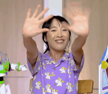 a woman wearing a purple shirt with unicorns on it is smiling