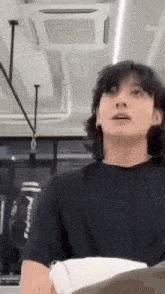 a man with long hair is standing in a room with a ceiling fan and a punching bag .