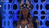 a woman in a feathered costume is standing in front of a blue wall .