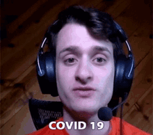 a man wearing headphones and a microphone with the words covid 19 on his face