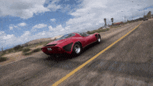 a red car is driving down a road with a yellow line on it