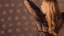 a woman in a sequined dress is dancing with her arms in the air