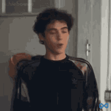 a young man with curly hair is standing in a room with his eyes closed and his mouth open .