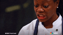 a woman in a chef 's uniform making a funny face with the nbc logo in the corner