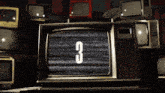 a stack of old televisions with the number 3 displayed on the screen