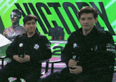two men sitting in front of a victory sign