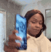 a woman is taking a selfie with a cell phone in her hand .
