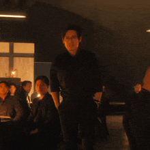 a man in a black shirt stands in a dark room