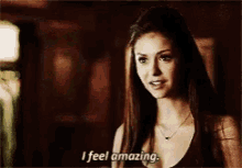 a woman is standing in a dark room and saying i feel amazing .