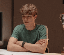a young man sitting at a table with his arms crossed