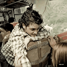 a man in a plaid shirt is hugging another man on a train