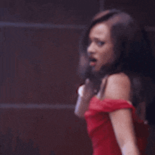 a woman in a red dress is standing in front of a mirror and looking at herself .