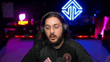 a man wearing headphones and glasses is sitting in front of a microphone in a dark room .