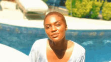 a woman is sitting in front of a pool and smiling