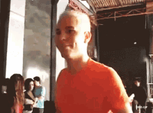 a man in an orange shirt is standing in a crowd