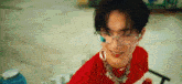 a young man wearing glasses and a red shirt is sitting on the floor .