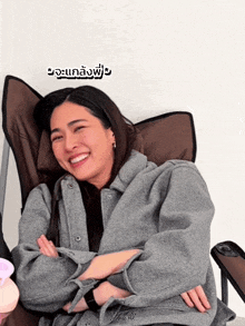 a woman is sitting in a chair with her arms crossed and a foreign language written above her head