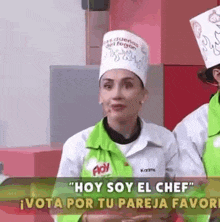 a woman in a chef 's hat is talking to a man in a kitchen .
