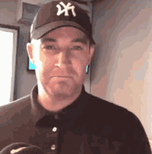 a man wearing a new york yankees hat makes a funny face