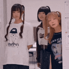 three girls are standing next to each other and one has a cutesy shirt on