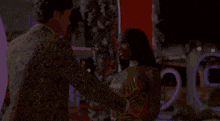 a woman in a gold dress is being held by a man in a suit