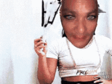 a woman in a white crop top is holding a white object in front of her face .