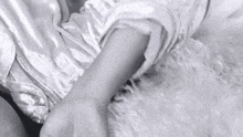 a black and white photo of a person 's arm laying on a blanket .