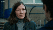 a woman with a police lanyard around her neck talks to another man