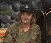 a woman wearing a la hat and a camouflage shirt