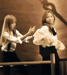 two women are dancing in front of a wall with a shadow of a person on it