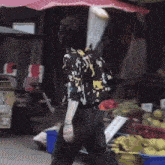 a person walking in front of a fruit stand with a sign that says ' a ' on it