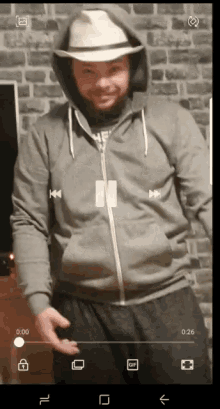 a man wearing a hoodie and a hat is being recorded on a cell phone