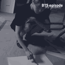 a black and white photo of a person drawing on a piece of paper with the words bts episode on it