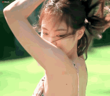 a woman in a bikini is holding her hair in a ponytail while looking at the camera .
