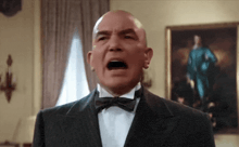 a bald man wearing a tuxedo and bow tie is screaming