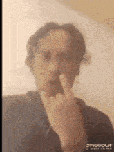a man is making a face with his finger on his nose .