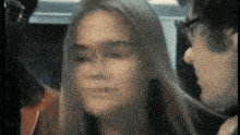 a man and a woman are sitting next to each other on a bus and looking at each other .