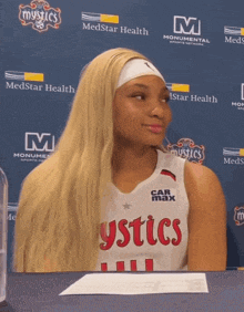 a woman wearing a mystics jersey sits in front of a medstar health backdrop