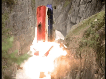 a red white and blue building is exploding on a cliff