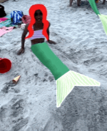 a girl in a mermaid costume is sitting on the sand