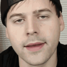 a close up of a man 's face with a black hat on